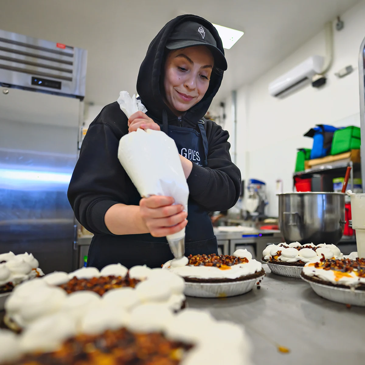 Staff piping whipped topping onto soft serve pies in the kitchen