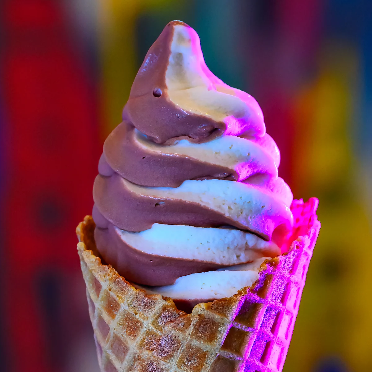 Pink and white Softserve swirl in a waffle cone against the colorful Magpies wall