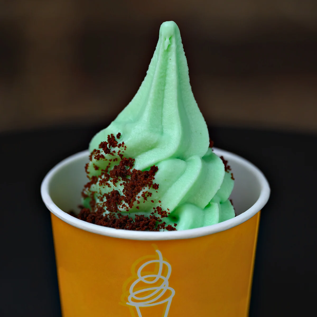 Mint-green Softserve with crumb topping in a yellow cup